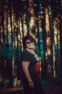 Young woman wearing sunglasses standing in forest