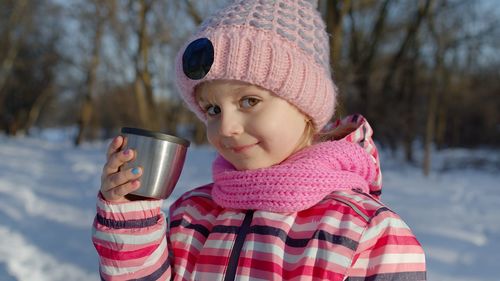 Portrait of cute boy drinking glass during winter