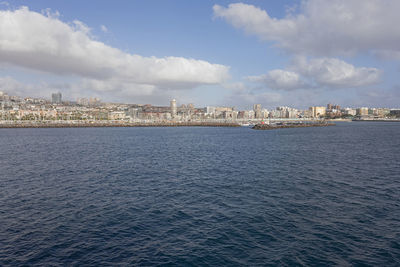 Sea by buildings against sky in city