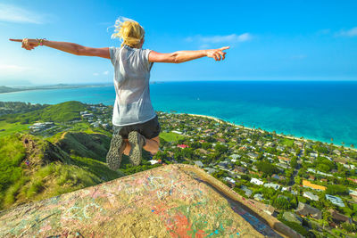 Rear view of man standing by sea against sky