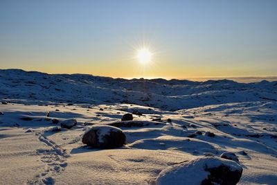 Scenic view of snowy landscape against clear sky during sunset