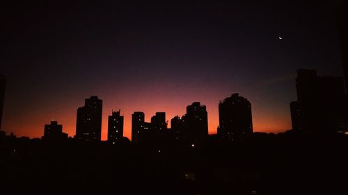 Silhouette buildings against sky at night