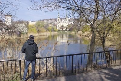 Rear view of man standing by bare tree in city