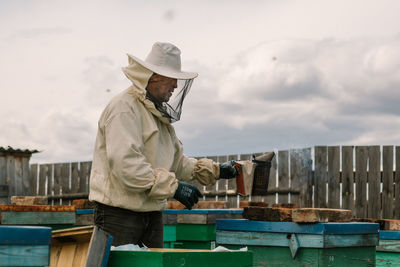 Beekeeper in a protective suit fumigates hives