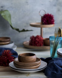 Close-up of flowers with kitchen utensils on table against wall