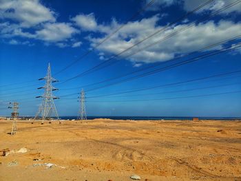 Electricity pylon on field against sky