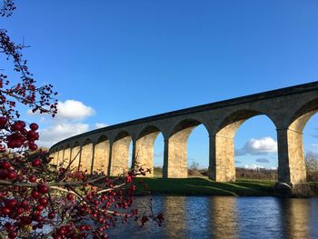 Arch bridge over river against sky