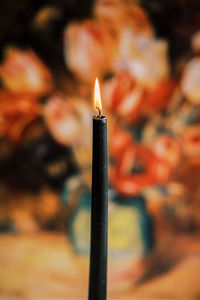 Close-up of a burning candle against the backdrop of a painting for a warm and moody vibe.