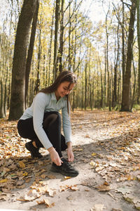 The girl ties her shoelaces. girl doing fitness in nature on a sunny autumn forest