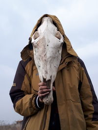 Person holding animal skull against sky