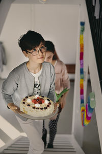 Boy carrying birthday cake while climbing up steps with sister at home