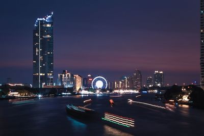 Illuminated modern buildings in city against sky at night