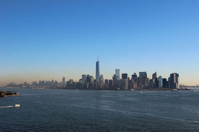 Sea by modern buildings against clear sky