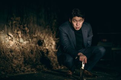 Young man looking away while sitting on land at night