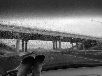 Low section of legs against empty road against bridge