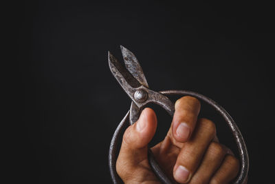 Close-up of man holding hand over black background