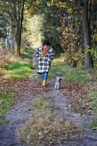 Rear view of woman walking on dirt road