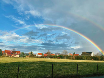 Scenic view of rainbow over field against sky