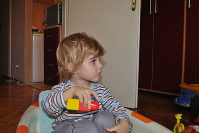 Cute boy sitting while playing with blocks at home