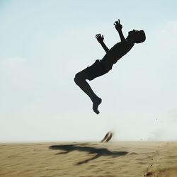 Rear view of woman jumping on beach