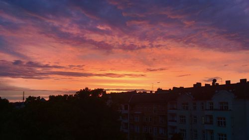 Silhouette buildings against cloudy sky during sunset