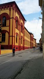 Rear view of man walking on street amidst buildings in city