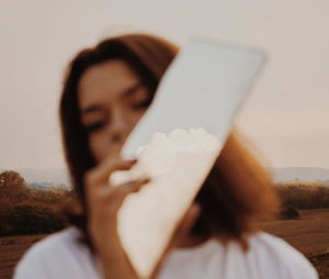 Close-up of woman holding mirror against sky