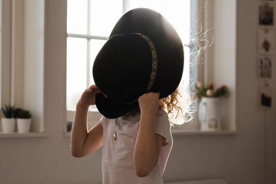 Portrait of a young girl playing with a hat covering her face