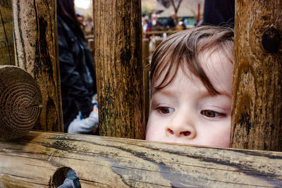 Portrait of cute girl peeking through fence