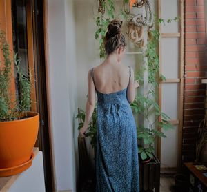 Rear view of woman looking at plants in home