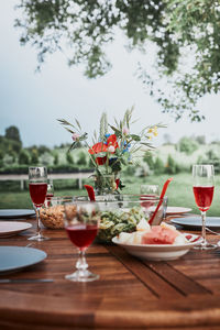 Dinner in an apple orchard garden on wooden table with salads and wine decorated with flowers