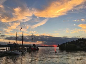 Sailboats moored on sea against sky during sunset