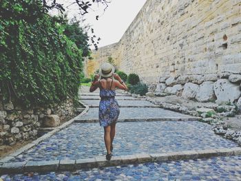 Rear view of woman walking on footpath