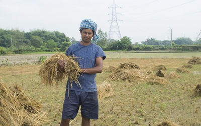Portrait of man holding rice paddy in agricultural field