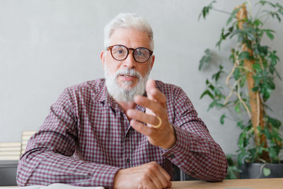 Portrait of mature man gesturing against wall