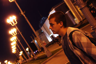 Side view of young man looking at illuminated night