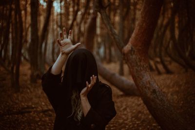 Full length of woman standing by tree trunk in forest