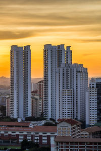 Modern buildings in city against sky during sunset