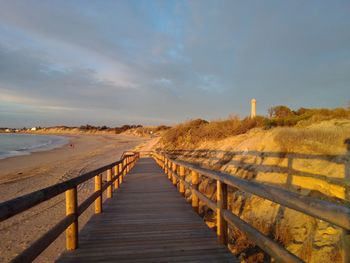 Boardwalk leading towards sea against sky