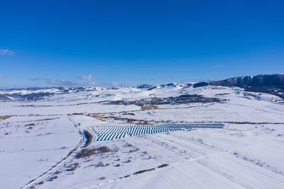 Aerial drone view of snow covered solar panel park, photovoltaic power station in the winter