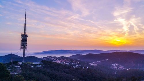 Communications tower in city during sunset