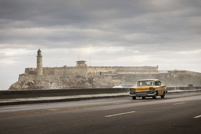 Cars on road against sky in city