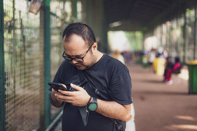 Young man using mobile phone while standing outdoors