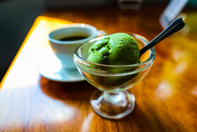 Close-up of drink served and green tea ice cream on table