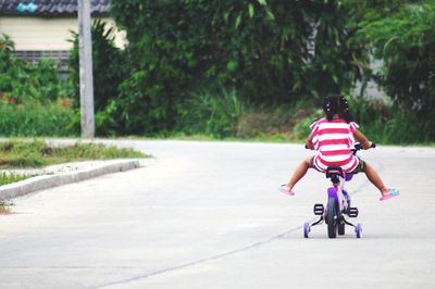 Rear view of girl riding bicycle on road