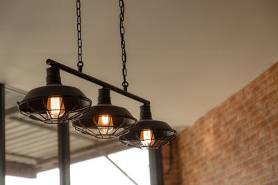 Low angle view of illuminated light bulb hanging on wall