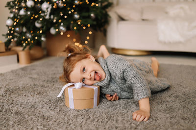 Portrait of cute girl playing with christmas tree at home