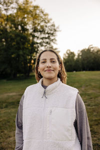 Portrait of smiling woman wearing jacket while standing in playground