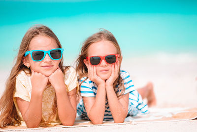 Portrait of smiling girls wearing sunglasses lying on beach