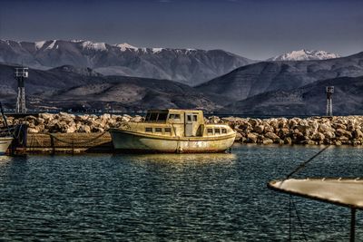 Sailboats in sea by mountains against sky